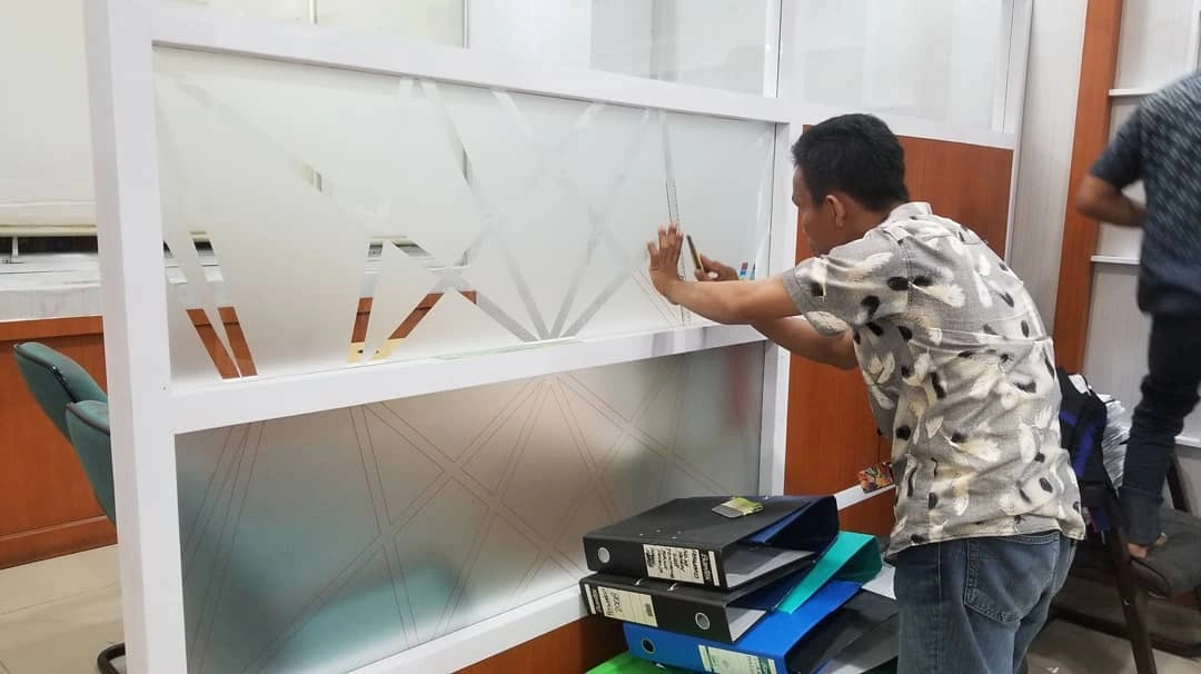 Proses pemasangan stiker sandblast oleh tim Bonafide Advertising